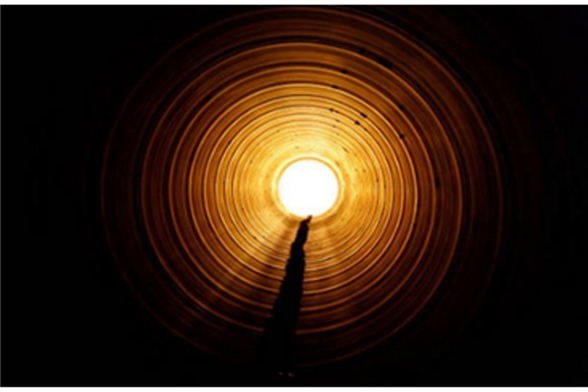 Light at the end of a drainage tunnel, figure walking toward it
